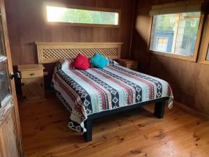 a bedroom with a bed with two pillows on it at Cabañas Lickanantay in Puerto Varas