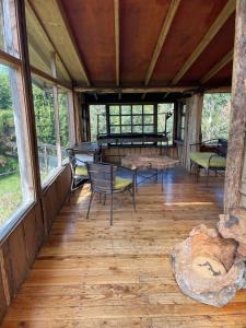 a large screened in porch with chairs and a piano at Cabañas Lickanantay in Puerto Varas