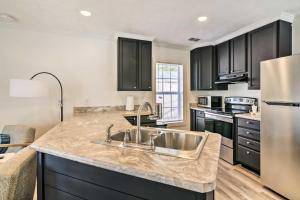 a kitchen with black cabinets and a stainless steel sink at Chic Cottage Retreat with Grill, 2 Mi to MSU! in Starkville