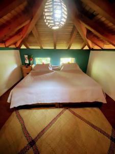 a bedroom with a large white bed with a chandelier at Troncones Point Hostel in Troncones