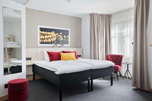 ウプサラにあるベスト ウエスタン ホテル スヴァーヴァのベッドルーム1室(ベッド1台、赤い椅子付)