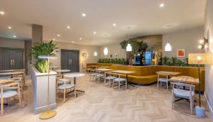 un restaurante con mesas y sillas y un sofá amarillo en Radisson Blu Hotel Dublin Airport en Cloghran