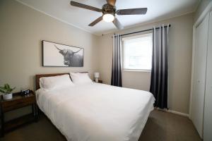 Schlafzimmer mit einem weißen Bett und einem Deckenventilator in der Unterkunft Adorable and Cozy Bungalow in Great Falls