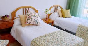 a room with two beds and a table with a lamp at Apartamento con vistas al mar en la playa de Vilagarcia - O Feitizo in Vilagarcia de Arousa