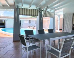 - une salle à manger avec une table, des chaises et une piscine dans l'établissement Villa le Moulin - Didier BERVILLE, au Gosier