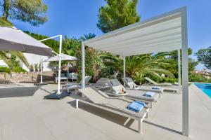 a patio with lounge chairs and umbrellas next to a swimming pool at Buenavista by Almarina Villas in Benissa
