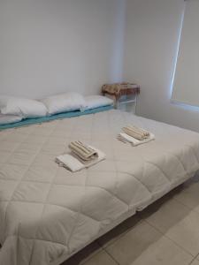 Una gran cama blanca con toallas encima. en APART OTERO en Ushuaia