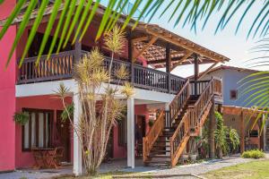a pink house with wooden stairs and palm trees at Suítes Las Flores Maresias in Maresias