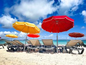 - un groupe de chaises longues et de parasols sur une plage dans l'établissement Princess Anouk Beachfront Orient Bay Deluxe 3 BDR, à La Baie-Orientale