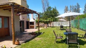 a backyard with a table and chairs and an umbrella at Pasillos del Viñedo in Cafayate