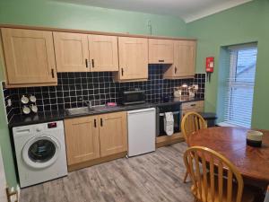 uma cozinha com uma mesa e uma máquina de lavar roupa em Heights View Apartment em Derry Londonderry
