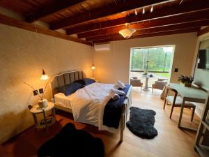 a bedroom with a bed and a table and a window at WoodStone Hotel Fazenda in Gramado
