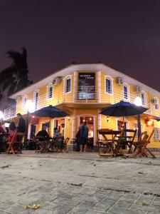 a yellow building with tables and umbrellas at night at Hospedaria Porto 27 in Porto Belo