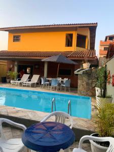 eine Terrasse mit einem Tisch und Stühlen neben einem Pool in der Unterkunft Lindo Sobrado Amarelo -próximo a praia in Mongaguá