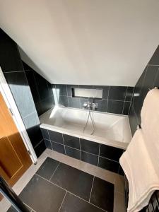 a bathroom with a white tub in a black tiled floor at Apt D in Old Grade 2 Converted Farmhouse in Market Weighton