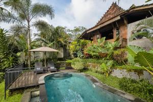an outdoor swimming pool in front of a house at Mandana Ubud Villa in Ubud