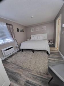 een slaapkamer met een groot wit bed en een tapijt bij Spacious Condo Walking distance to Weirs in Laconia