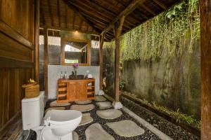 a bathroom with a toilet and a sink at Mandana Ubud Villa in Ubud