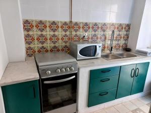 a small kitchen with a stove and a microwave at DAR Jamila à 8021 Béni khalled Tunisie in Dawwār al Frinine