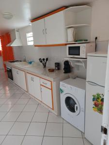 eine Küche mit weißen Schränken, einer Waschmaschine und einem Trockner in der Unterkunft Petit cocon in Les Abymes