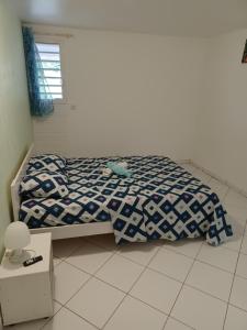um quarto com uma cama com um edredão azul e branco em Petit cocon em Les Abymes