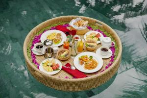 uma mesa com pratos de comida sobre a água em Mandana Ubud Villa em Ubud