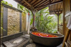 a large bath tub filled with flowers in a bathroom at Mandana Ubud Villa in Ubud