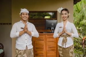 un homme et une femme debout devant un bureau, les mains devant dans l'établissement Mandana Ubud Villa, à Ubud