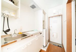 a white kitchen with a sink and a refrigerator at 優宿 Kitakoiwa in Tokyo