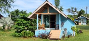 a blue cottage with a porch and chairs in a yard at Miss You Beach Resort Koh Mak in Ko Mak