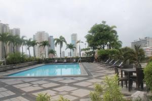 a swimming pool with chairs and a table and buildings at Pearl Manila Hotel in Manila