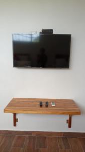 TV de pantalla plana en la pared con mesa de madera en Apartamentos Mundo Maya, en Flores