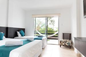 a bedroom with two beds and a balcony at Ocean Blue Hotel in Olón