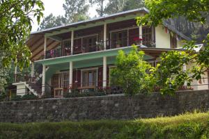 a house with a stone retaining wall in front of it at Mowgli Town Homestay/Resort in Nainital