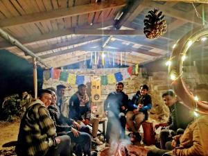 un groupe de personnes assises autour d'un feu dans une pièce dans l'établissement Mowgli Town Homestay/Resort, à Nainital