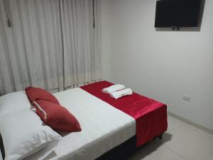 1 dormitorio con 1 cama con almohadas rojas y blancas en Apartamento turístico amoblado Barbosa en Barbosa
