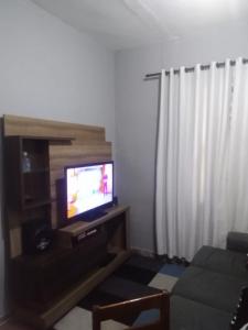 ein Wohnzimmer mit einem TV und einem Sofa in der Unterkunft Praia Grande Apartamento Aconchegante pertinho da Praia - 300m in Praia Grande
