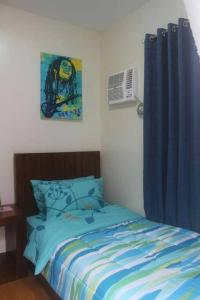 1 dormitorio con cama y cortina azul en Pontefino Prime Townhouse 4BR with Wifi & Pool, en Batangas