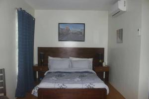 1 dormitorio con 1 cama con cabecero de madera en Pontefino Prime Townhouse 4BR with Wifi & Pool, en Batangas