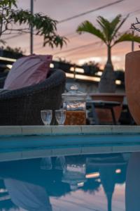 a swimming pool with two glasses and a table with at Le Coin d'Azur in Petite Île