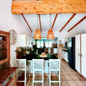 a kitchen with white cabinets and a table and chairs at Sky Tyde's Beach House in Port Shepstone