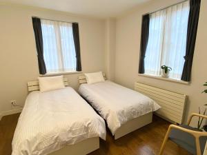 two beds in a room with two windows at LOHABO Sapporo Art park in Sapporo