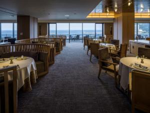 uma sala de jantar com mesas, cadeiras e janelas em Pearl Star Hotel ATAMI em Atami