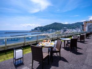 un restaurante con mesas y sillas en un balcón con vistas al océano en Pearl Star Hotel ATAMI, en Atami