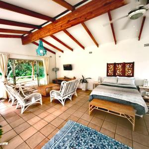 a bedroom with a bed and chairs in a room at Sky Tyde's Beach House in Port Shepstone