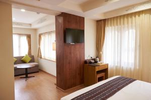 um quarto de hotel com uma cama e uma televisão na parede em The Willows Hotel, Bhutan em Thimphu