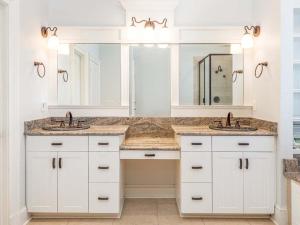 Baño blanco con 2 lavabos y espejo en Villa Mariposa, en Tybee Island