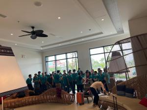 eine Gruppe von Menschen, die grüne Hemden tragen, die in einem Zimmer stehen in der Unterkunft Toà Nhà Apec Mandala Wyndham Phú Yên in Tuy Hoa