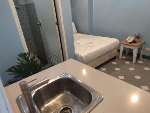 a bathroom with a sink and a bed in a room at Glory Hotel Cubao in Manila