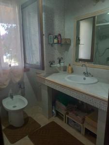a bathroom with a sink and a toilet and a mirror at la casa del glicine in Iglesias